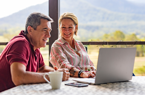 Picture of a couple on a patio table smiling and looking into a laptop photo