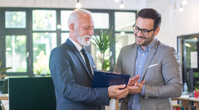 Advisor shaking hands with husband with wife sitting next to him in office setting photo