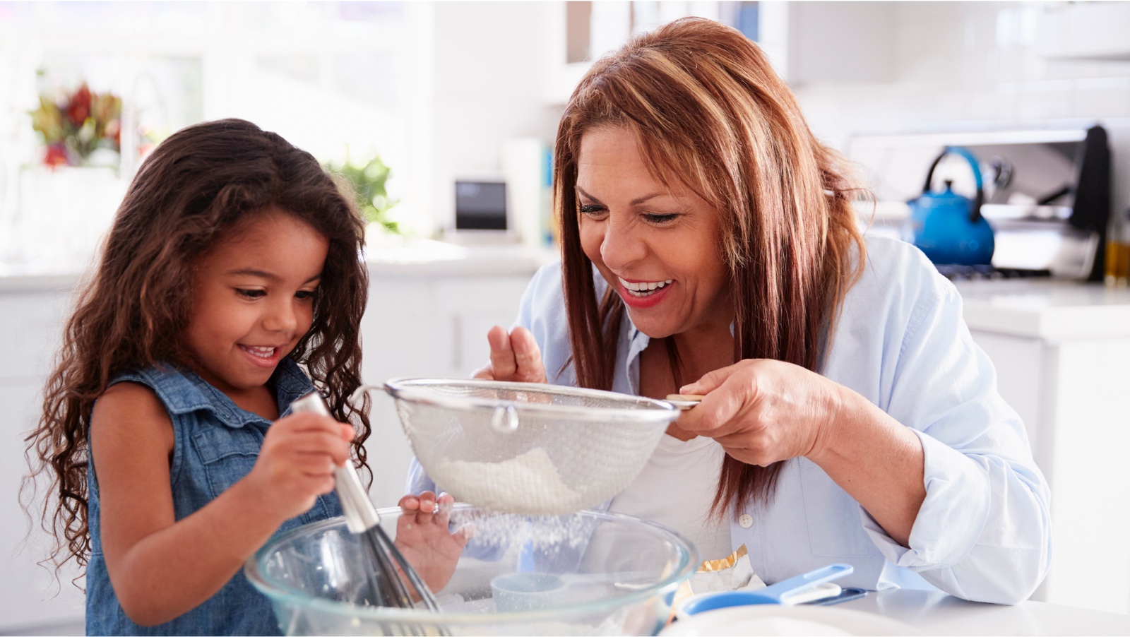 A picture of a grandma and granddaughter baking in a kitchen