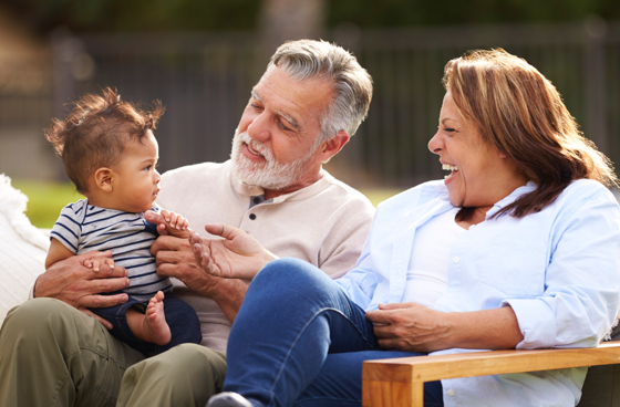 A picture of an older couple sitting on a bench with a baby