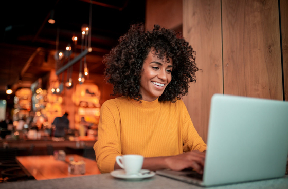 A picture of a young girl in a café working on a laptop