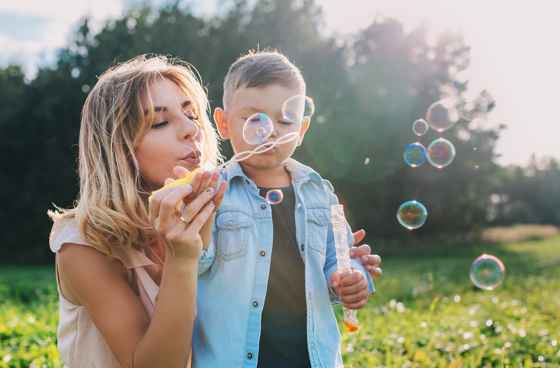 A picture of a mother and son blowing bubbles in an outdoor setting