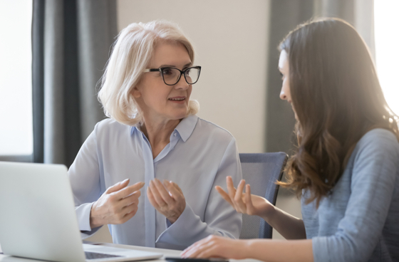 A picture of an senior woman talking to a younger girl in an office setting