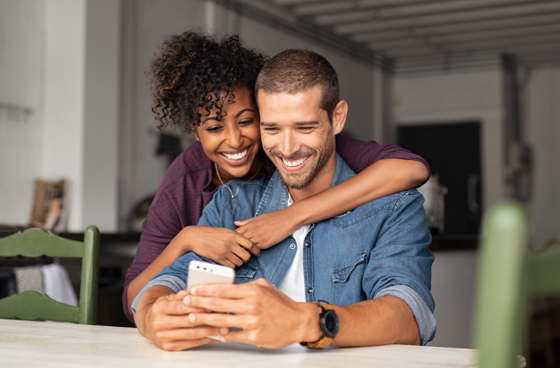 A couple hugging and looking at an iphone