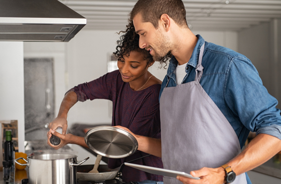 A picture of a couple of cooking together in a kitchen