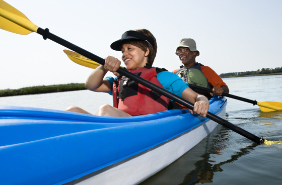 A picture of an older man kayaking with a little boy