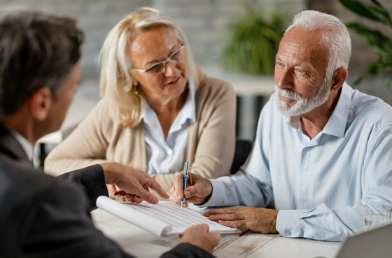A picture of an advisor going over paperwork with an older couple