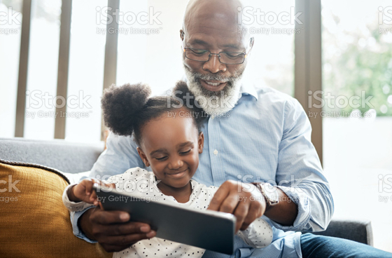 A picture of a grandpa and granddaughter looking at an ipad
