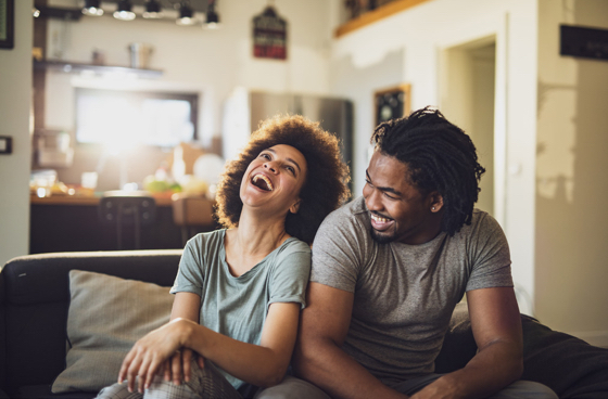 A picture of a couple sitting on a couch laughing