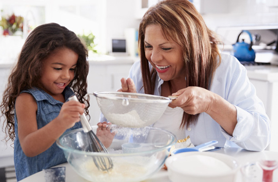 A picture of a grandma and granddaughter baking in a kitchen